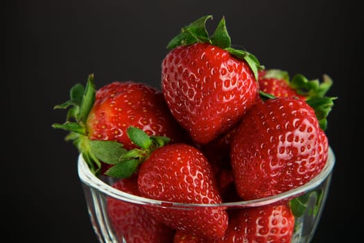 Strawberry in glass container on black background