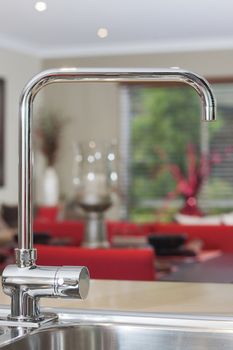Photo of the kitchen water tap with blurred living area as a background