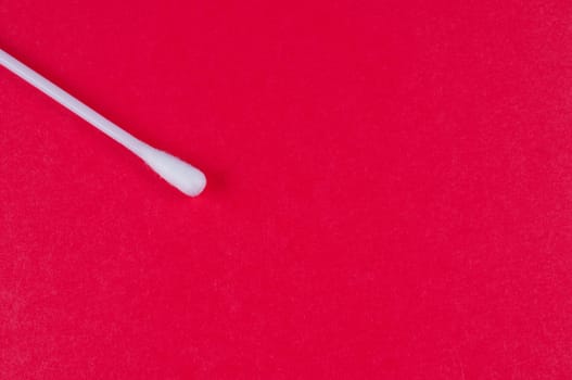 Cotton bud on red background close up