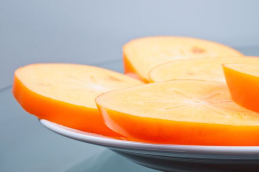 Cuted persimmon few pieces on plate close up