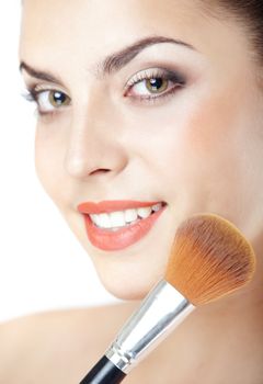 Smiling lady with makeup brush on a studio background