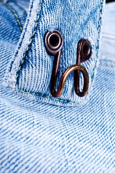 Heavily used hook on pair of blue jeans trousers brass
