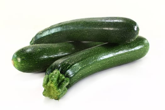 three green zucchini on a white background