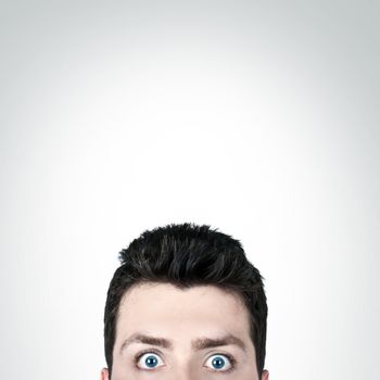 Young man surprised with wide open eyes and copy space