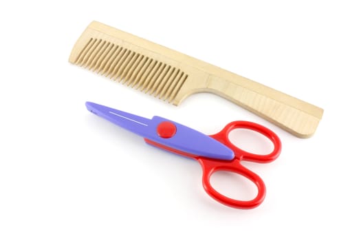Wooden comb and scissors over white