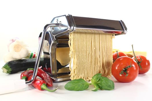 Spaghetti in a pasta machine with vegetables and basil