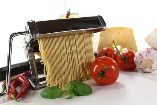 Spaghetti in a pasta machine with tomatoes, chili peppers and basil