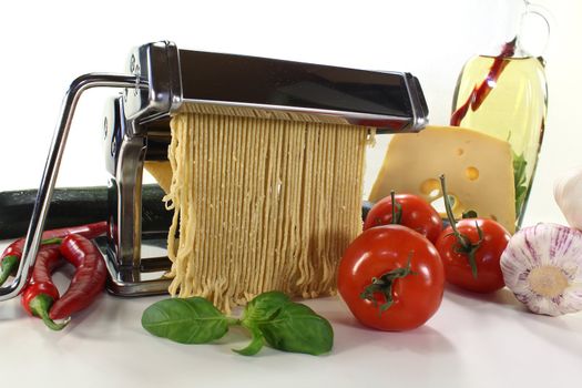 Spaghetti in a pasta machine with tomatoes, cheese and basil