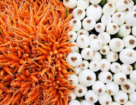 Pile of orange carrots and white onios at farmers market