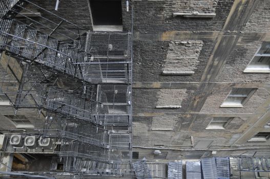 Photo looking down the exterior of an old building with fire escape. 