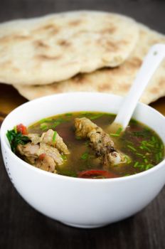 Chicken soup with homemade bread on rustic background