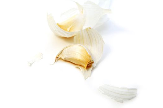 one clove and skin of the garlic bulb on white background