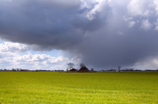 Dutch farm house covered with dark cloud before shower