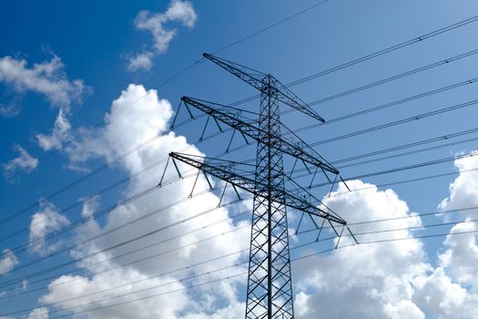 electricity high-voltage line over blue sky with puffy clouds