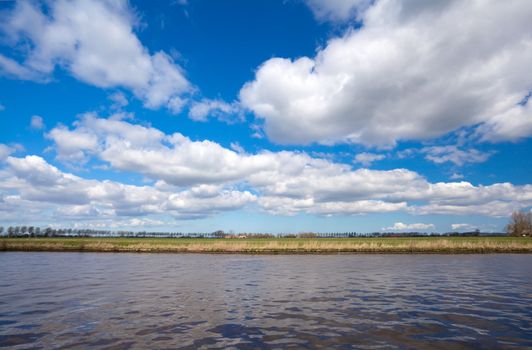 lines of land, water and blue sky with blue puffy clouds