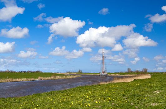 green spring pasture with curved river with ship and beautiful blue sky