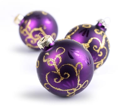 Three purple Christmas balls on white, shallow DOF