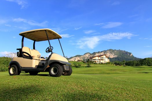 Golf cart on path, pretty green grass and blue sky background