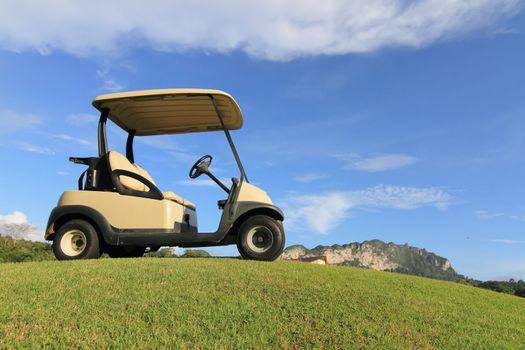 Golf cart on path, pretty green grass and blue sky background