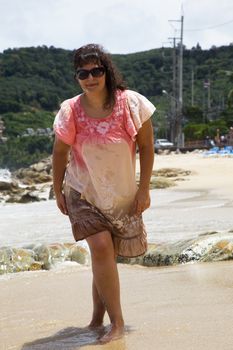 Brunette in a pink dress walking on the beach of Patong. Thailand.  Phuket