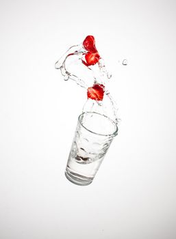 falling red ripe strawberry with glass of watert with splash