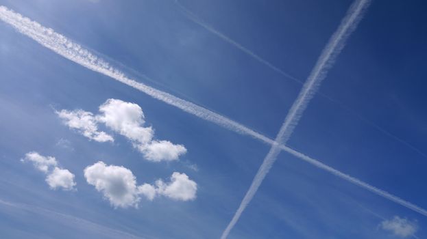 Condensation from airplanes build a cross on blue skies