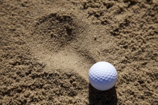 a golfball landing in a sand bunker on a golf course