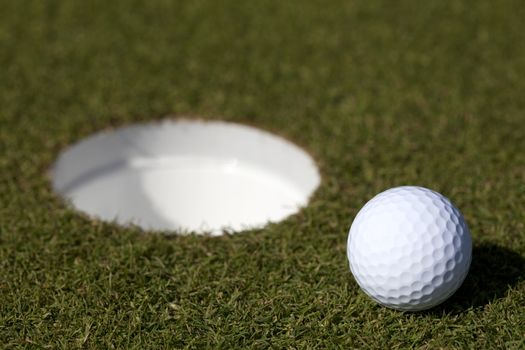 A golf ball sits near the hole on a putting green