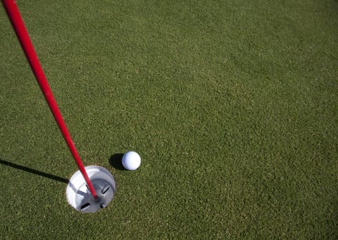 A golfball comes to rest near the hole - with copyspace in the green