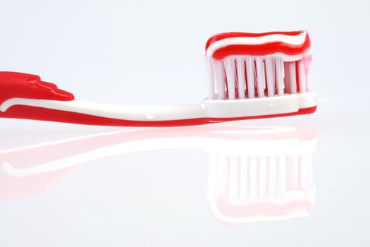 Red toothbrush on reflecting white background