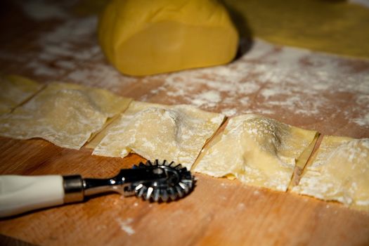 Preparation of homemade Ravioli with veal stuffing on wooden plate - shallow depth of field