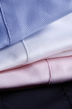 textile background - white, pink and light blue business shirts stacked - plenty of copyspace