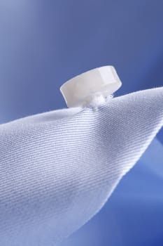 textile background - close-up of a button of a light blue business shirt on blue background