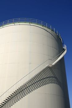 spiral staircase around oil storage and blue sky