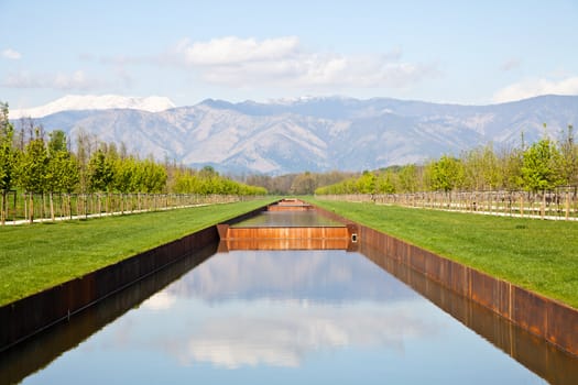 Italy - Water pool in green field with Alps mountains on background