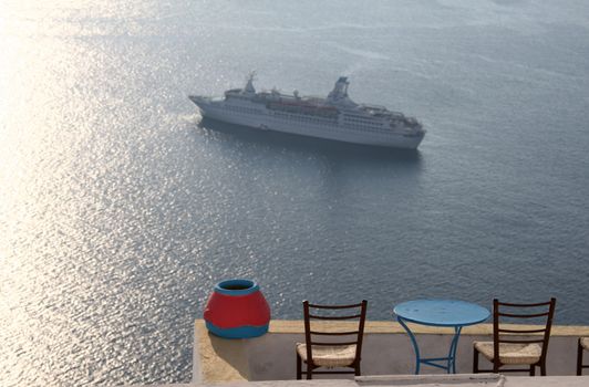 Tables and stools on Santorini with cruise ship in background