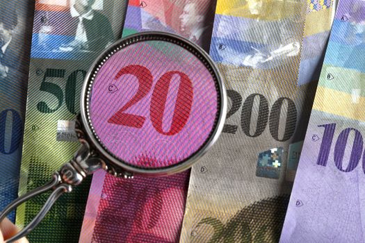 Swiss bank bills with magnifying glass