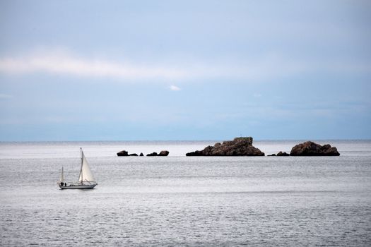 Sailboat passes rocks nearby Dubrovnik in Croatia