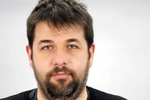 Portrait of a smiling, friendly dark hair ordinary middle age man over light grey bacground.