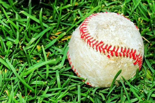 Sport background: old ans used baseball in the green grass field