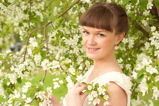 beautiful young brunette woman with the apple tree on a warm summer day