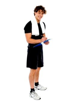 Full length portrait of male fitness trainer preparing dieting chart