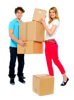 Handsome guy holding stack of cardboard boxes while woman doing the placement