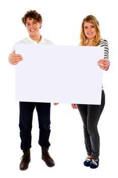 Adorable young couple promoting blank banner ad isolated over white
