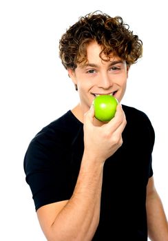 Young man eating fresh healthy green apple looking at camera