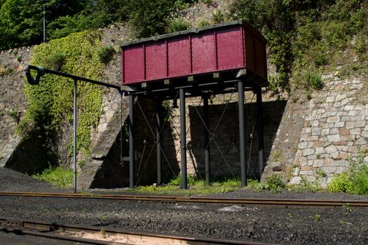 A water storage tank painted purple with a hose on a steam railway track.