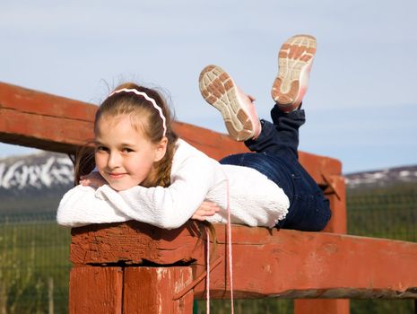 A girl lies on the balance beam in an open sports field