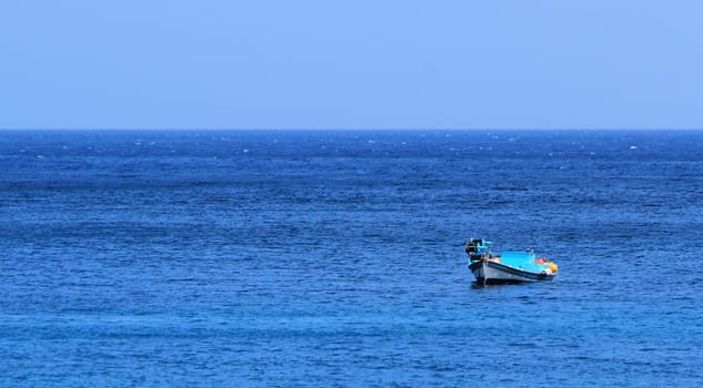 Colorful small boat alone on the calm sea by beautiful weather