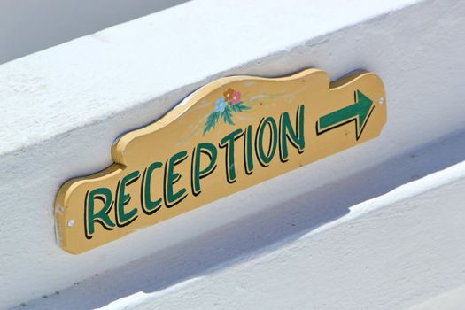 Colorful hotel reception desk sign with arrow.