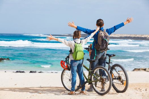 Back view of girl with her mother having a weekend excursion on their bikes on a summer day in beautiful sea landscape